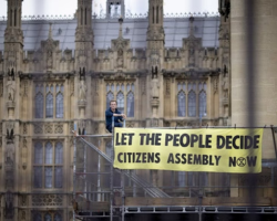 Les panels de citoyens devraient-ils déterminer la politique climatique ? C'est ce que demande un militant d'Extinction Rebellion devant le parlement à Londres à l'automne 2022. Keystone / Tolga Akmen